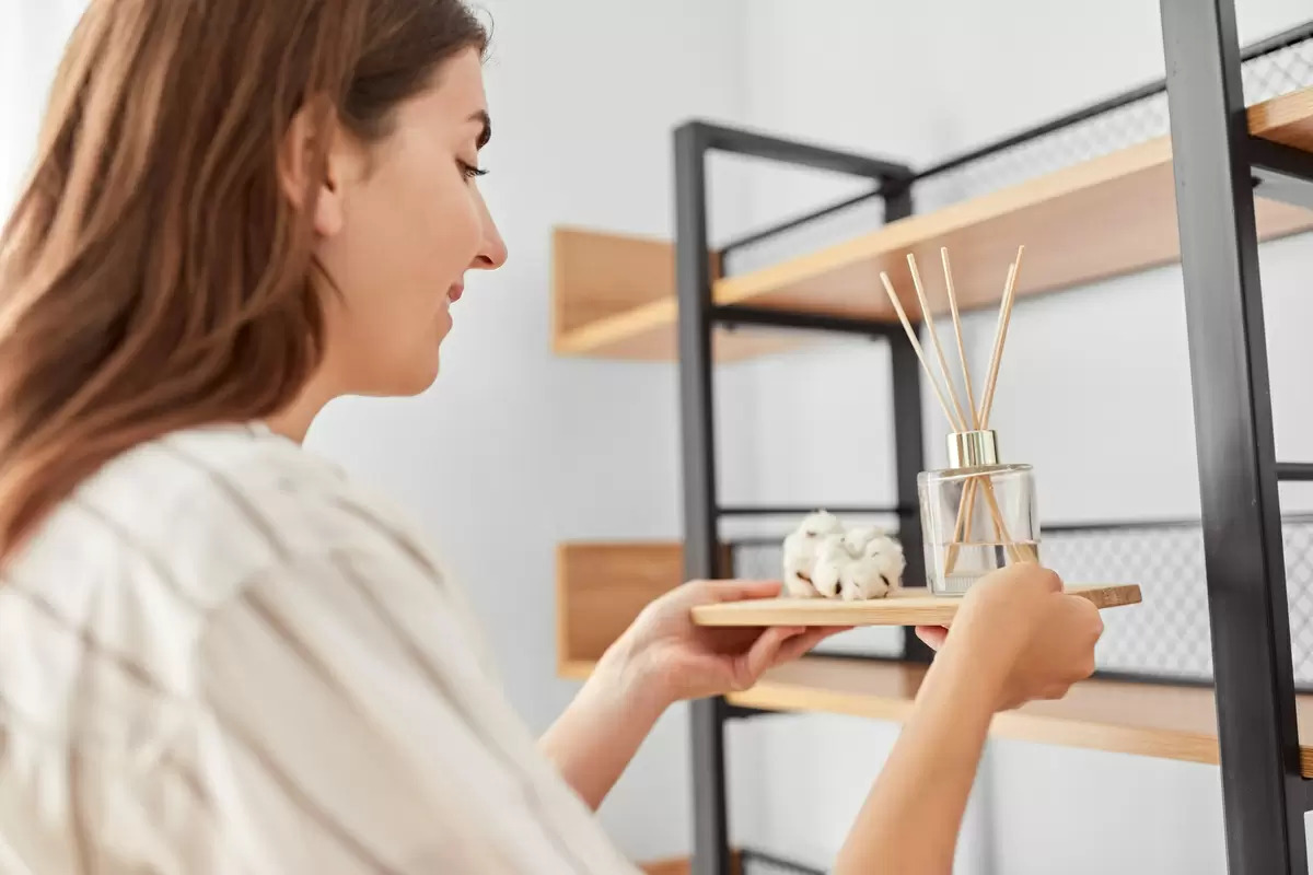 Woman placing reed diffuser on shelf